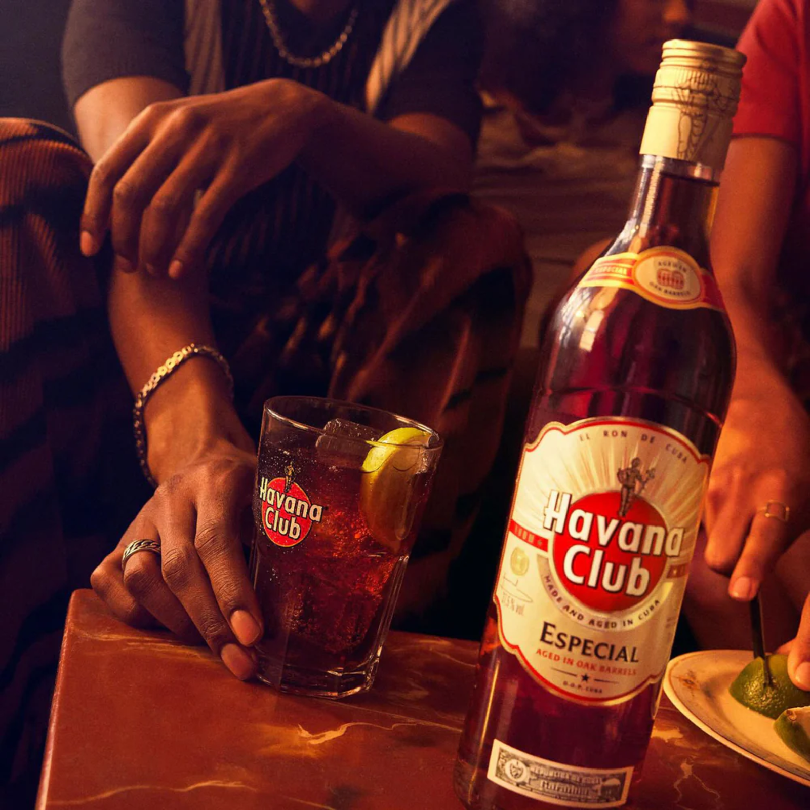 Havana Club bottle and glass on a bar counter with people in the background