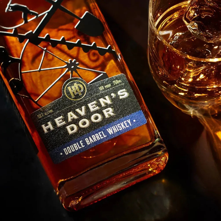 Heaven's Door Double Barrel Whiskey bottle with a glass of whiskey on a dark surface