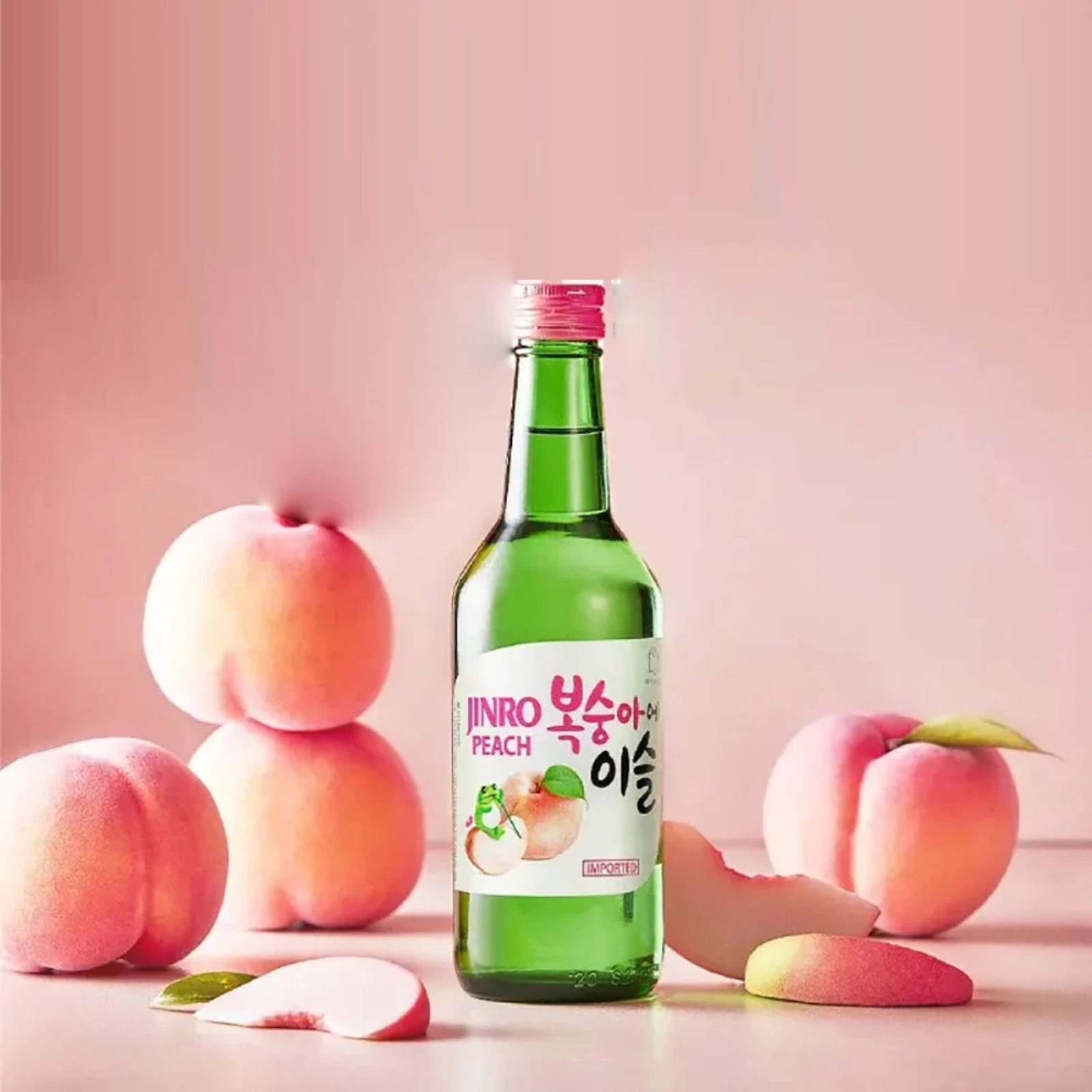 Green bottle of Jinro Peach soju with peaches on a pink background